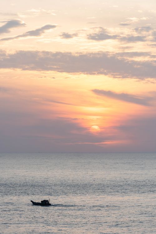 Free A tranquil boat ride at sunset in Vũng Tàu, Vietnam, with a colorful sky and calm sea. Stock Photo