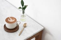 大理石桌上摆着一杯配有植物和勺子的卡布奇诺，散发着极简主义的氛围