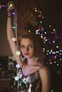 一个时尚的女人拿着灯串在圣诞树在节日的设置