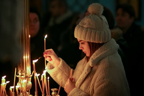 Woman in Brown Fur Coat and Cap Holding Lighted Candles