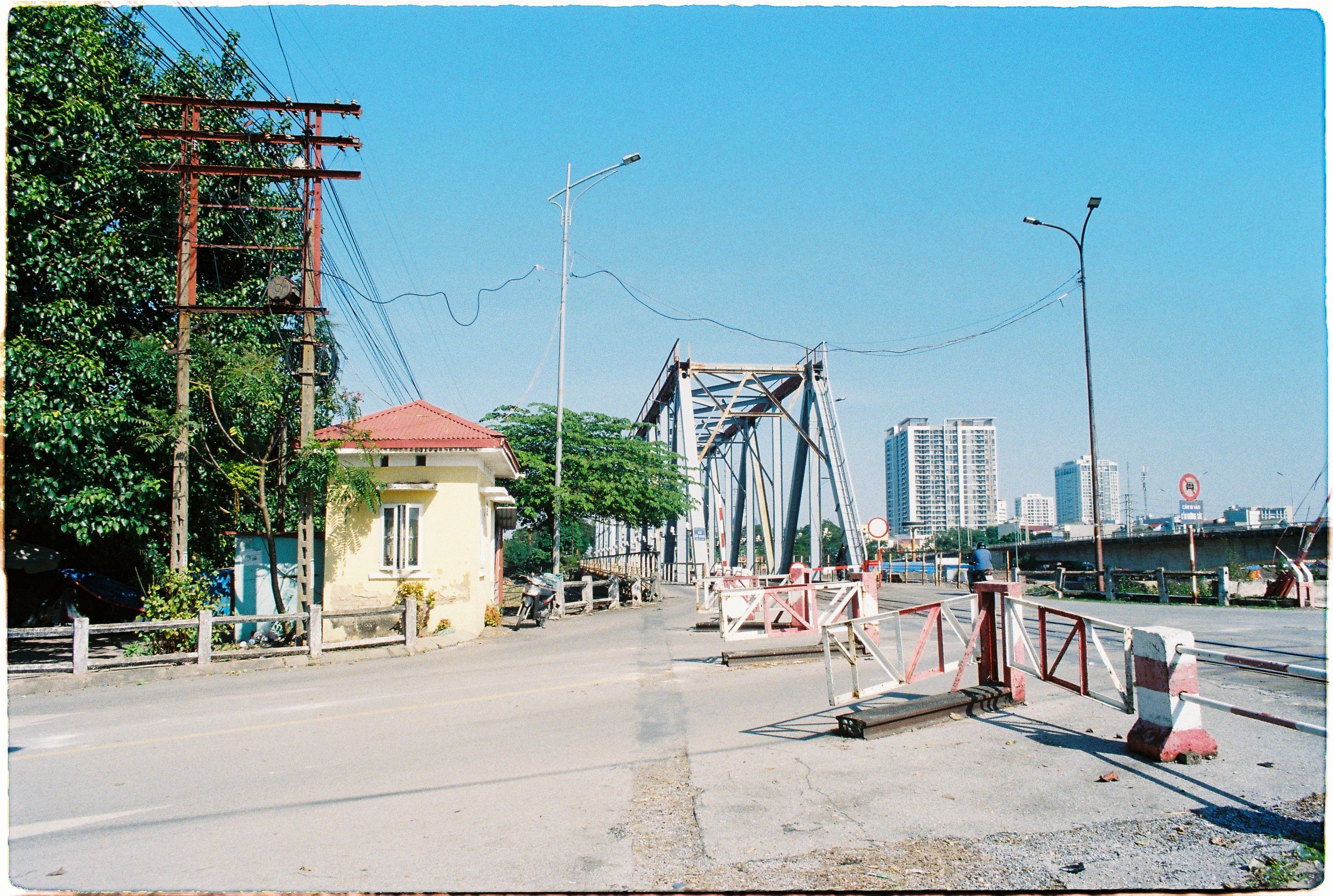 A bright image featuring a bridge and roadside building against a clear sky in an urban area.