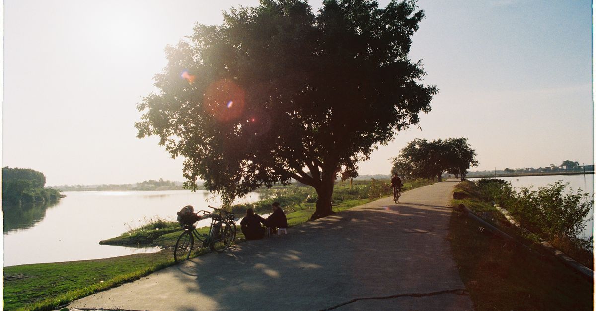 Serene Riverside Path with People and Bicycles · Free Stock Photo