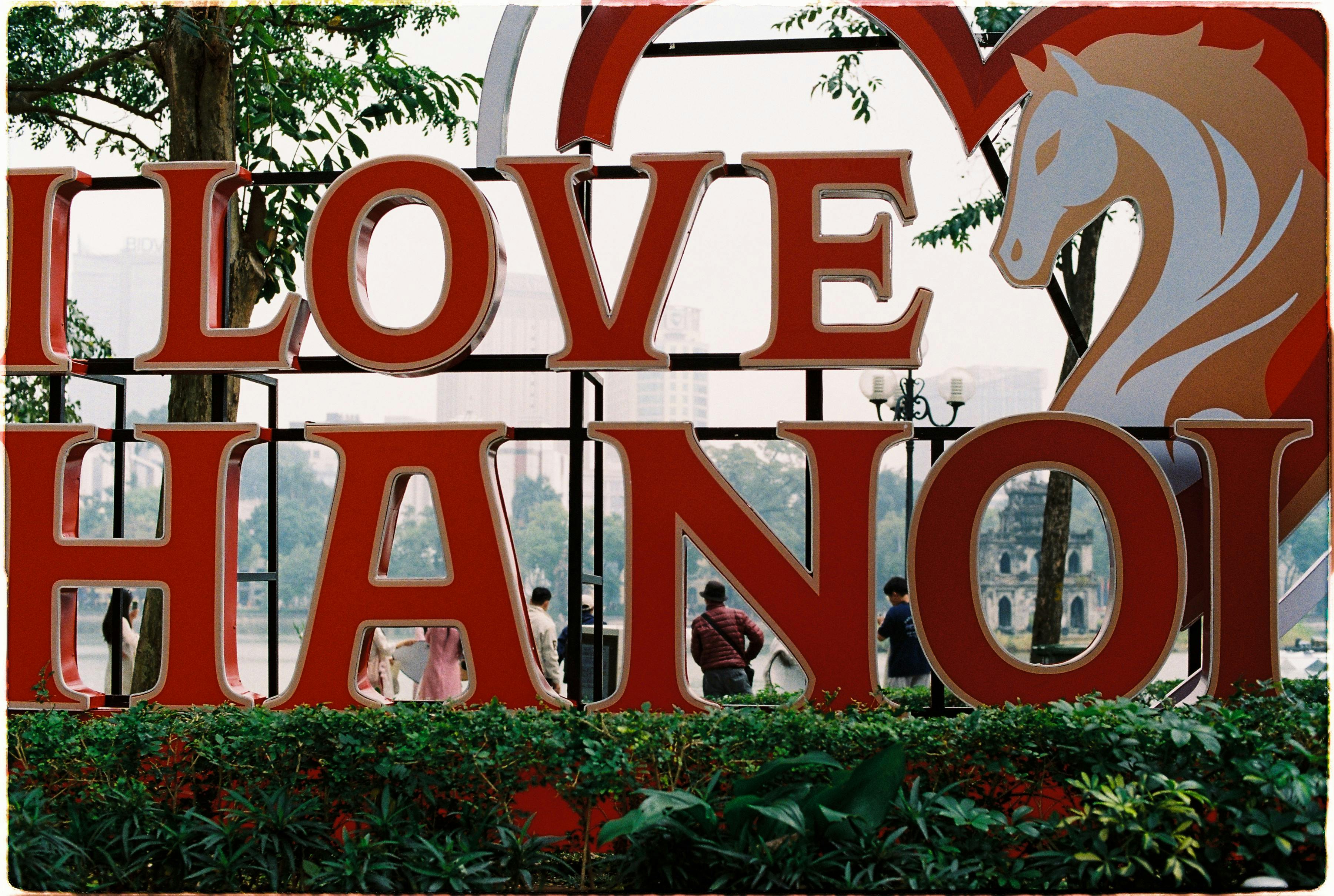 Colorful 'I Love Hanoi' sign with people in urban park setting, showcasing Hanoi's charm. - Hanoi