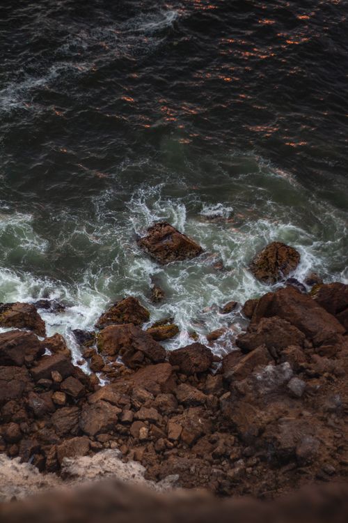 Free Aerial view of waves crashing against rugged rocks along the Lima coast, Peru. Stock Photo