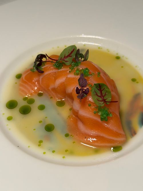 Free Close-up of salmon sashimi with herbs in a decorative sauce, perfect for gourmet dining. Stock Photo