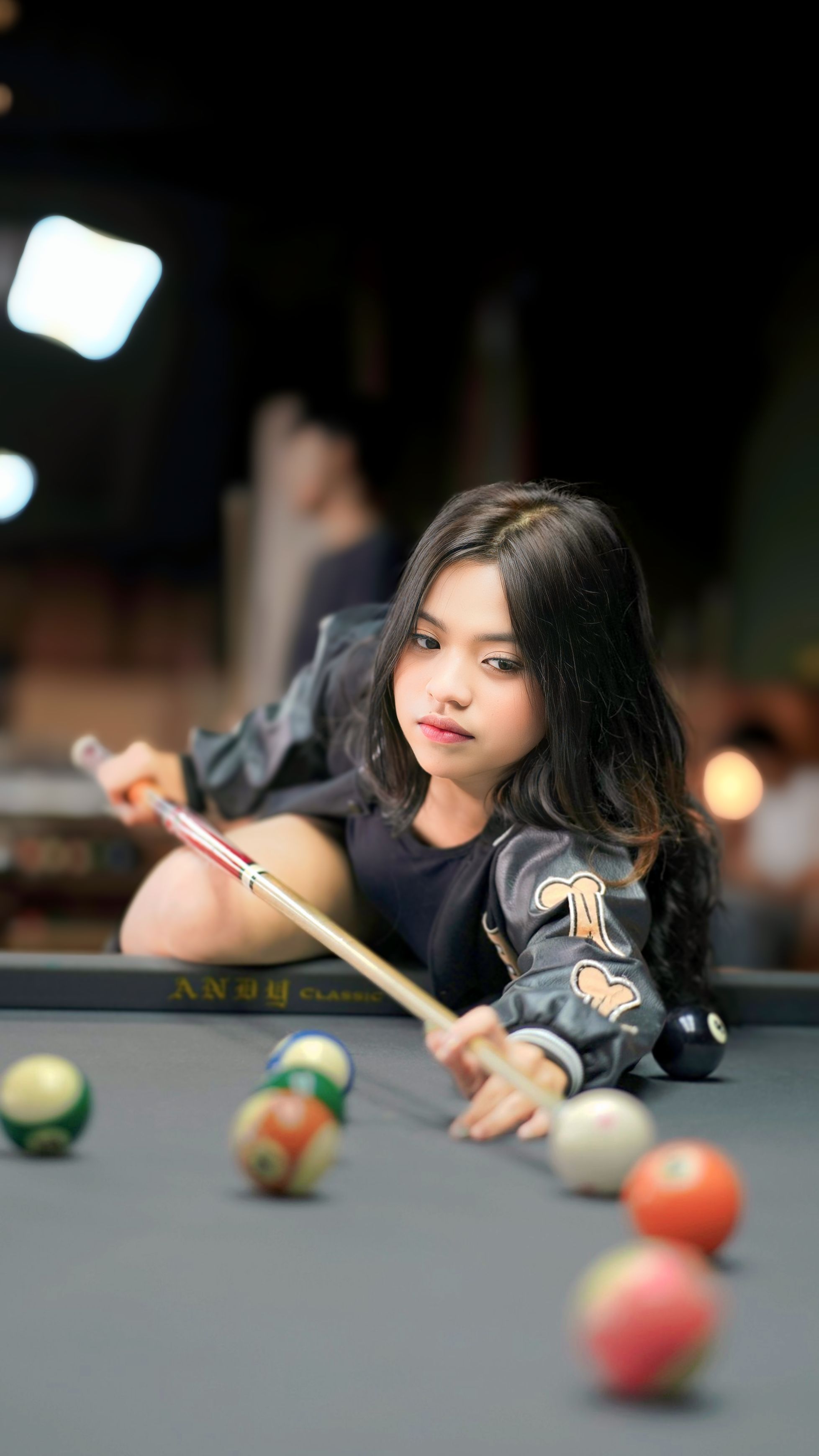 Young Woman Concentrating on Pool Shot Indoors