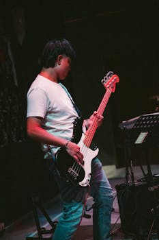 A guitarist performs energetically on stage at a live music event in Kuantan, Malaysia, showcasing vibrant youth culture.