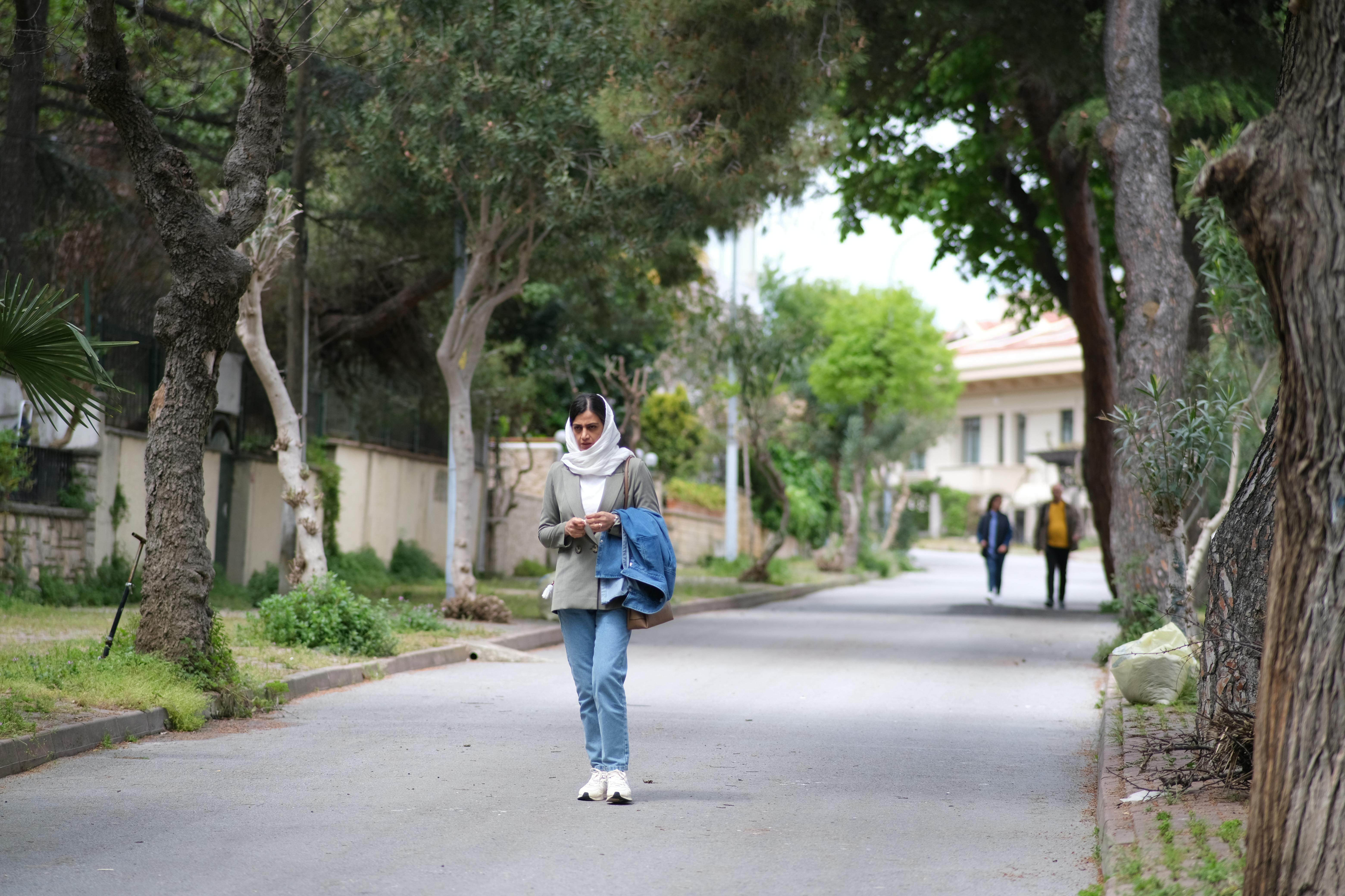 De franc Una dona passejant per un carrer amb arbres en un tranquil barri d'Istanbul, que respira calma i tranquil·litat. Foto d'estoc