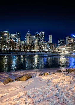 Stunning view of Calgary's skyline reflecting on the river during winter night.