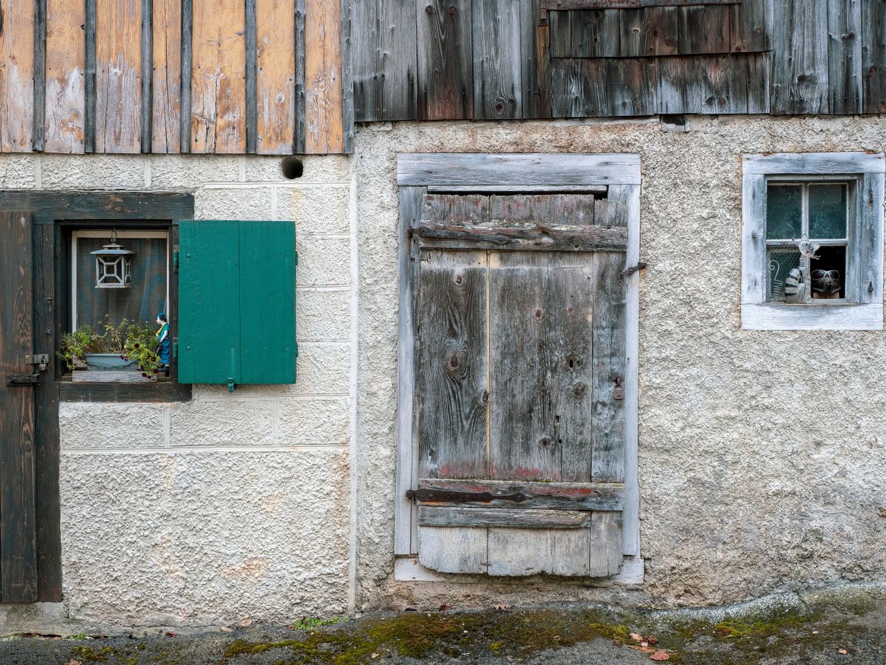 a rustic barn wall with a weathered wooden door and two small charming