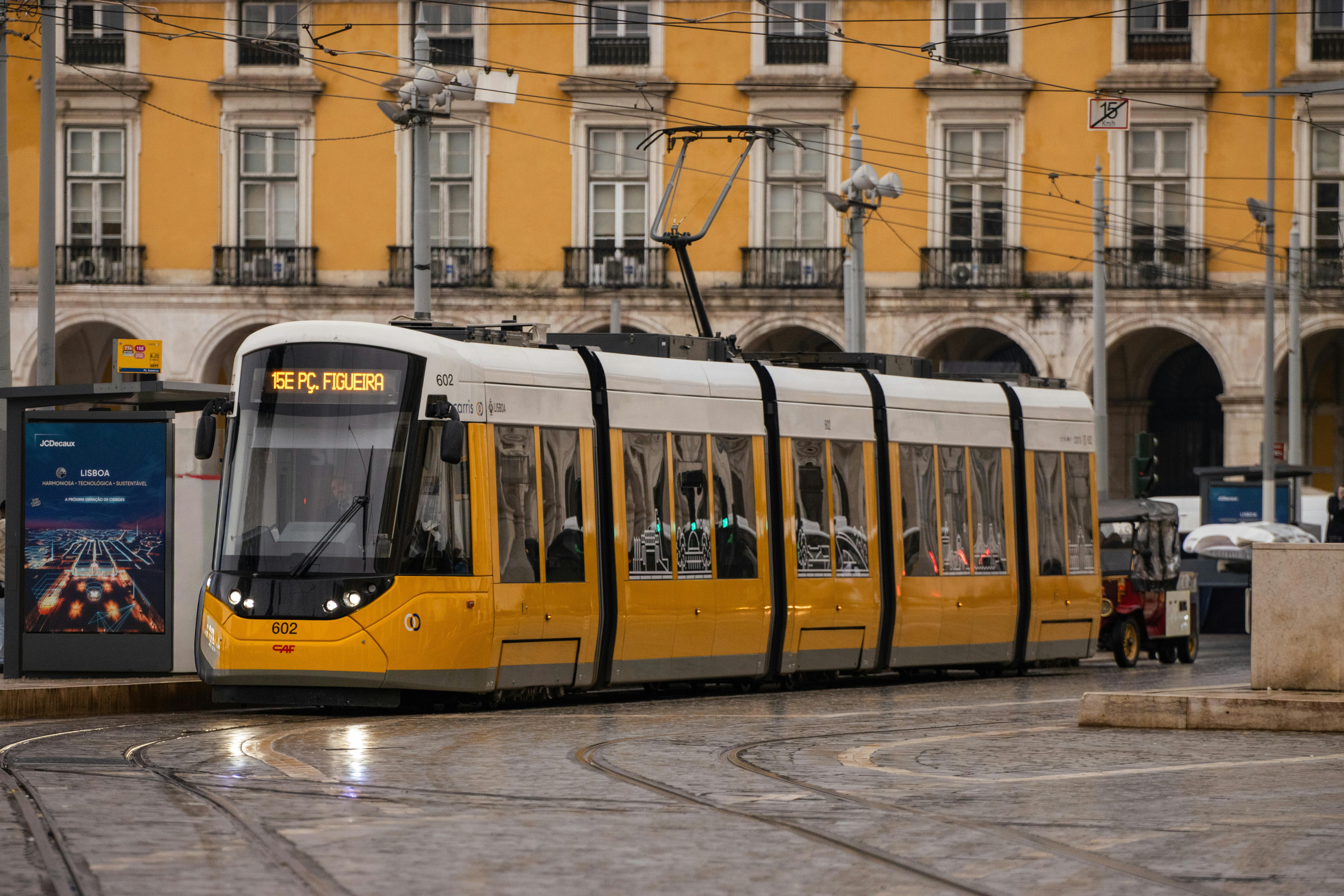 A classic yellow tram passing through Lisbon, Portugal's historic streets, showcasing Portuguese architecture.