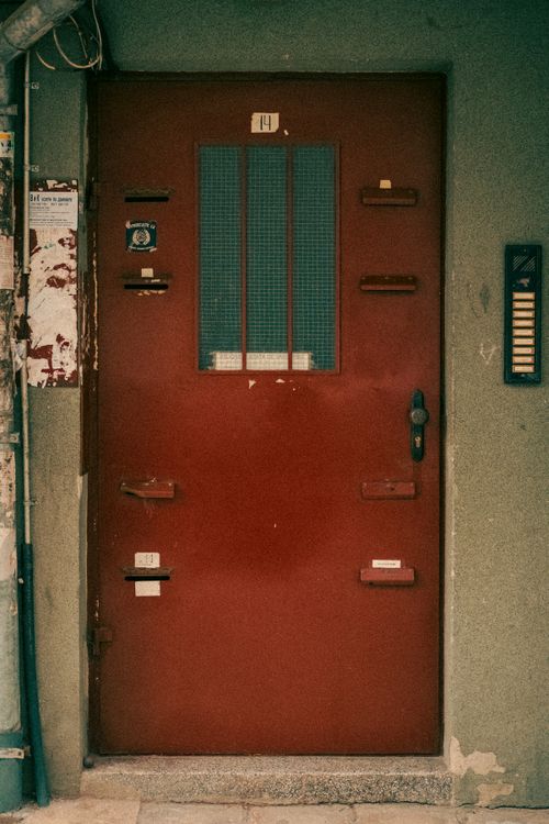 Free Old red metal door with grid window panels and industrial features, evoking urban nostalgia. Stock Photo