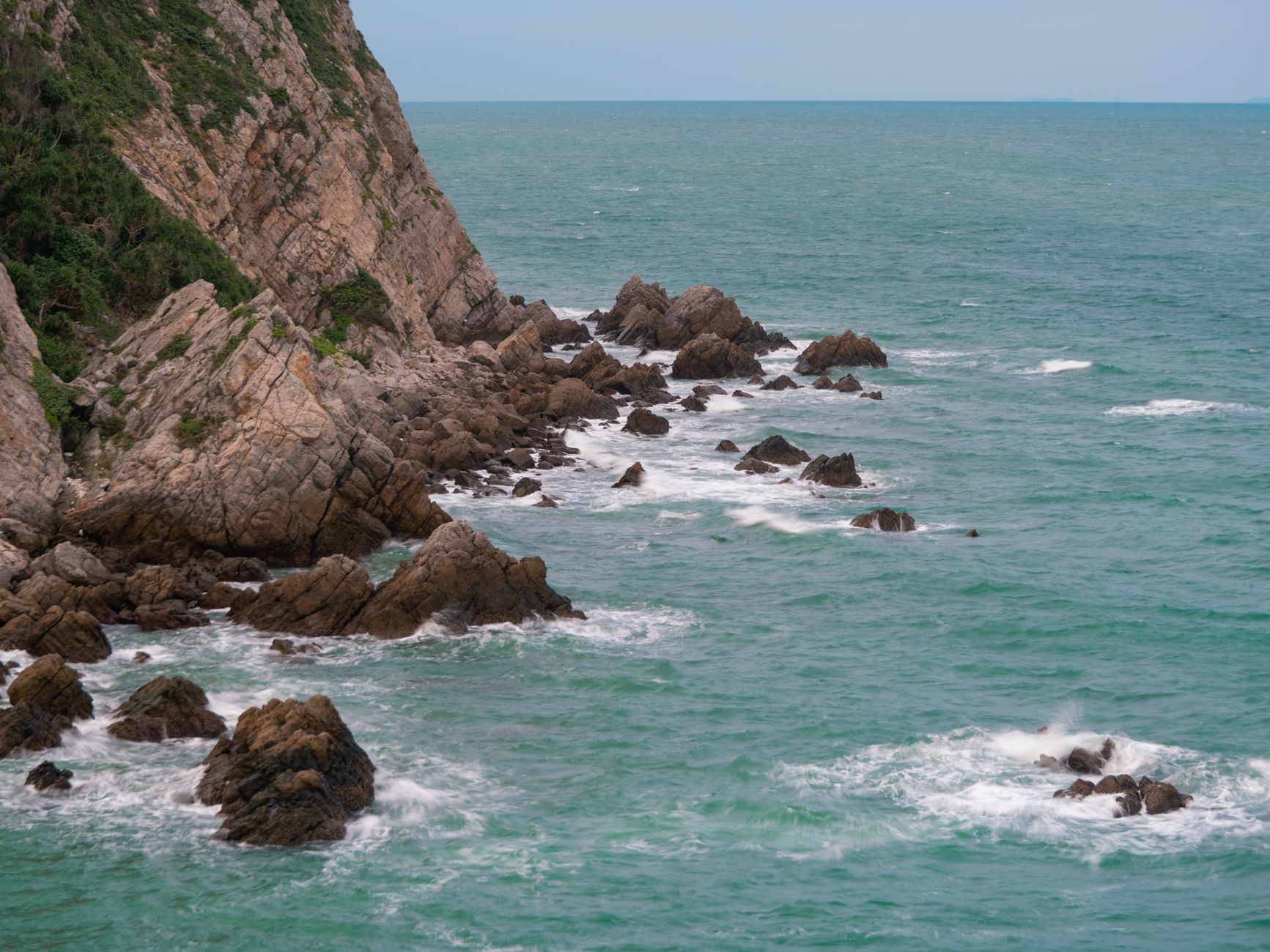 Captivating view of rocky coastline in Quảng Ninh, Vietnam amid vibrant turquoise waters.
