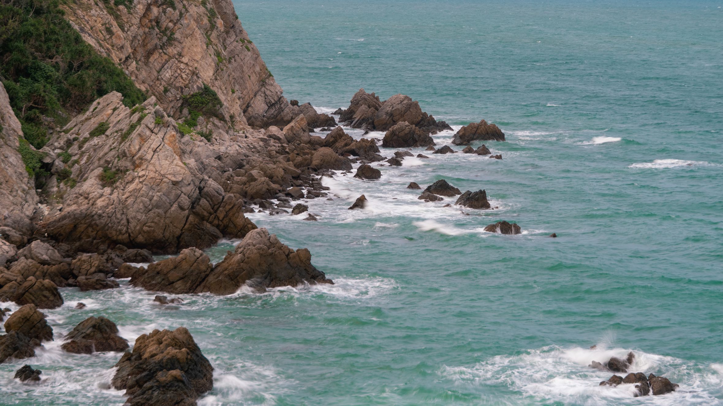 Captivating view of rocky coastline in Quảng Ninh, Vietnam amid vibrant turquoise waters.