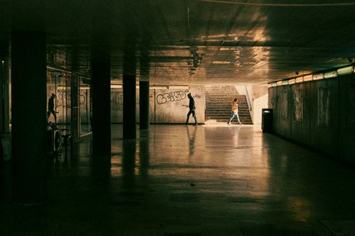 Free Moody shot of people walking through an urban underground passage with graffiti. Stock Photo