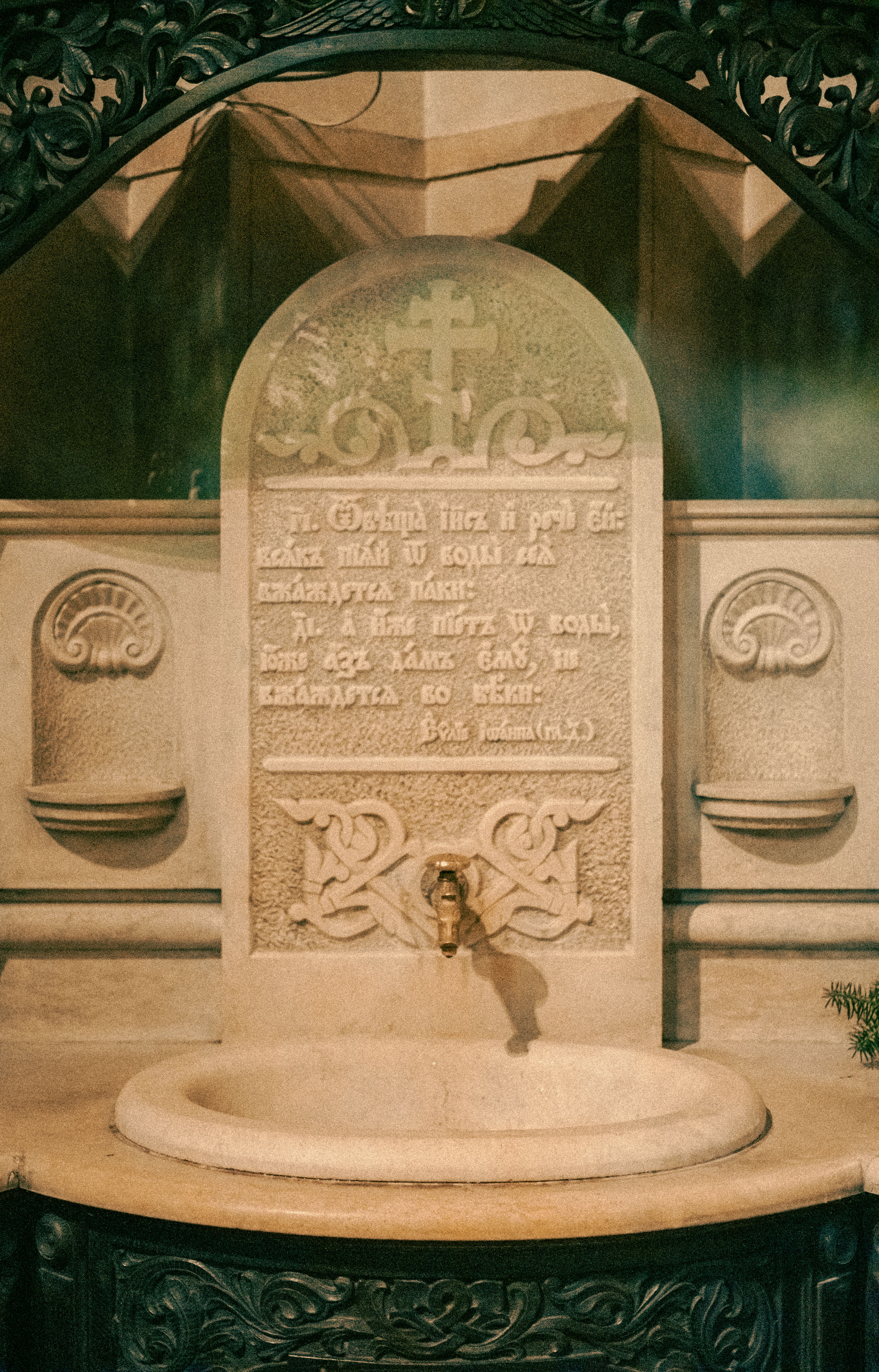 Intricately carved stone font with cross and inscriptions inside a historic church in Varna, Bulgaria.