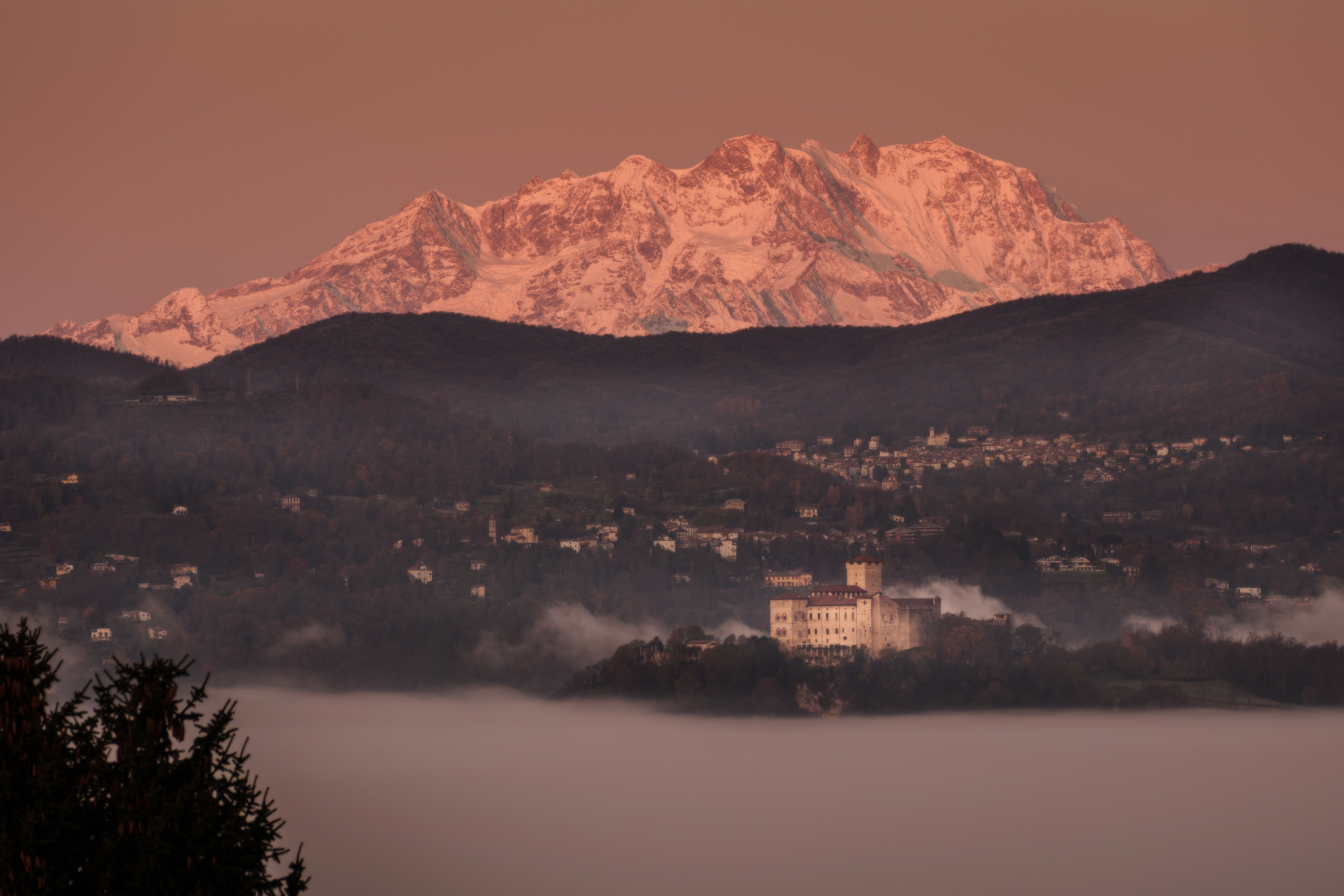 Une vue à couper le souffle sur des montagnes enneigées et une vallée brumeuse au lever du soleil, mettant en valeur une beauté naturelle sereine.