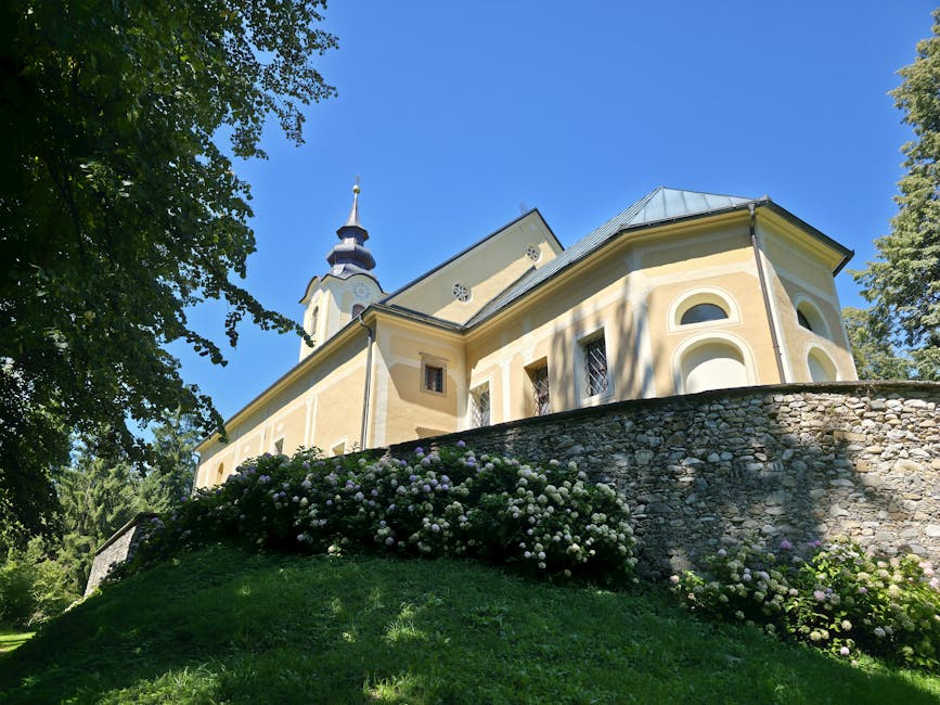 A picturesque ancient church surrounded by lush greenery under a vibrant blue sky in summer