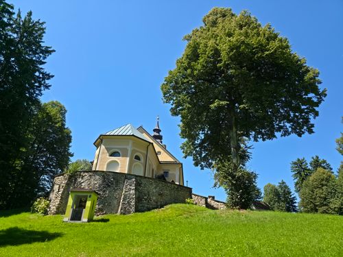 Free A historic church surrounded by lush greenery on a clear summer day in Slovenia. Stock Photo