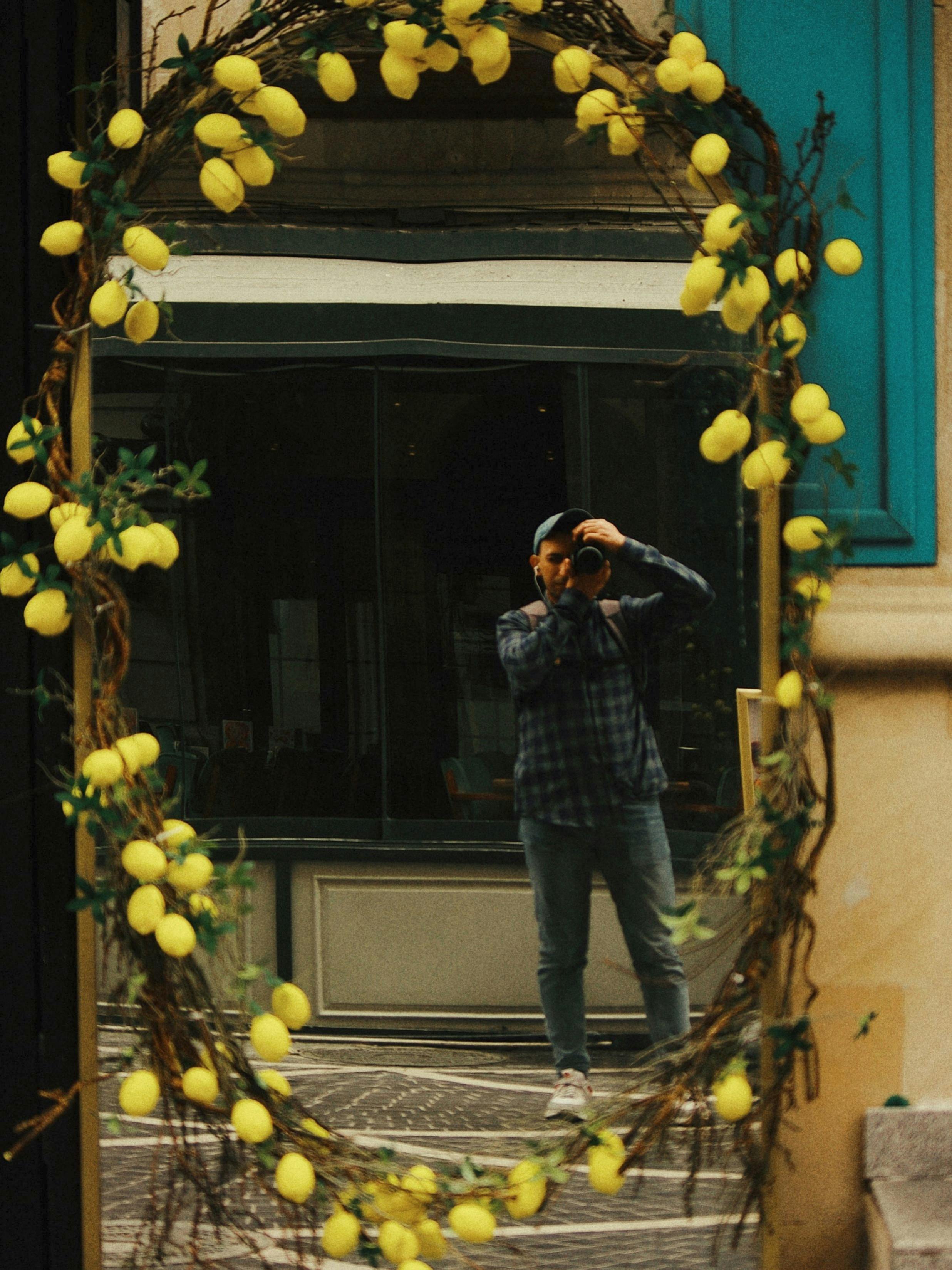 De franc Reflex d'un autoretrat en un mirall decoratiu amb marc de llimona en un carrer urbà. Foto d'estoc