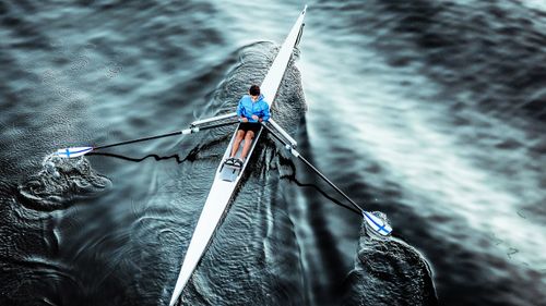 Free Aerial view of a man rowing a single scull on calm waters, dressed in a blue jacket. Stock Photo