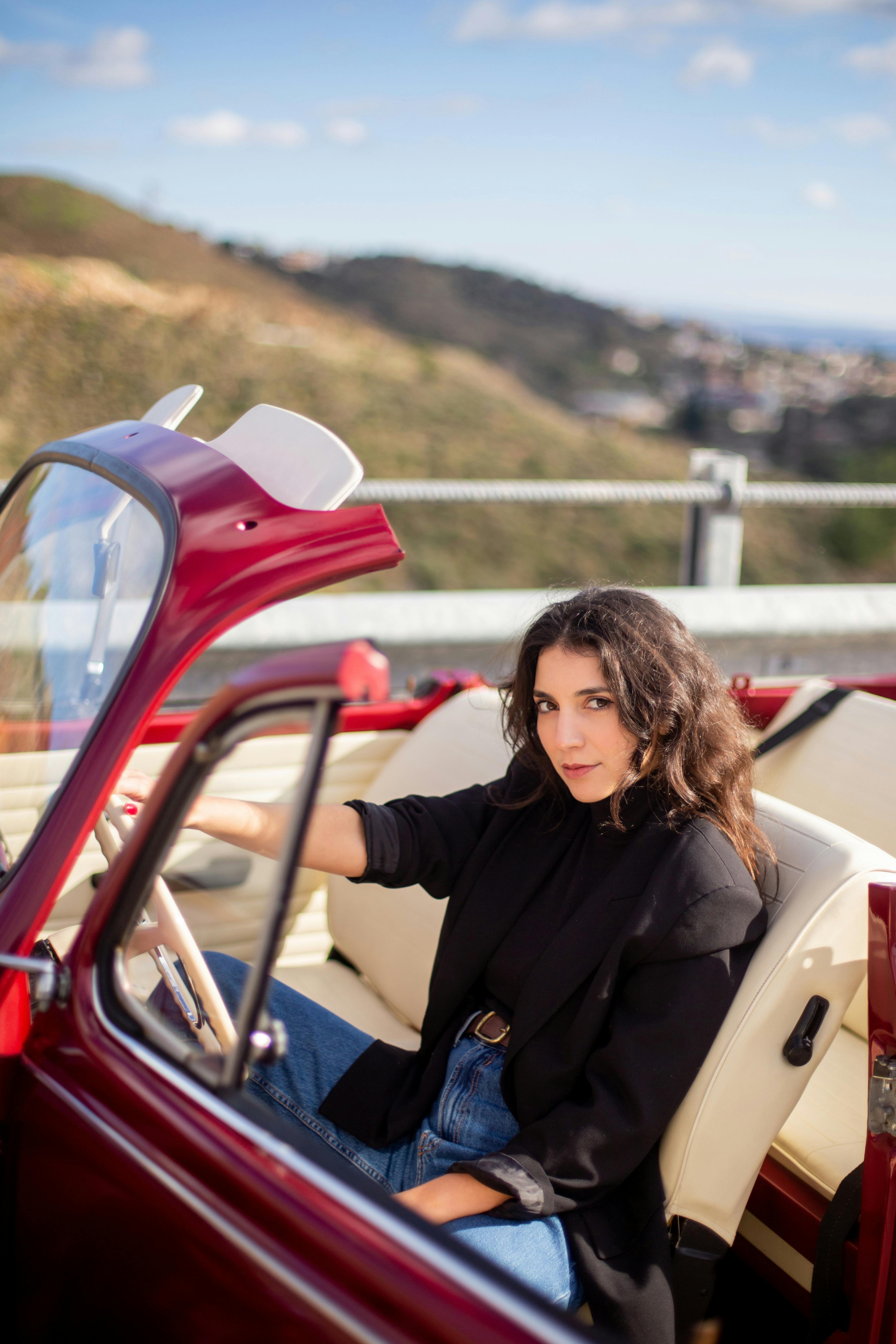 De franc Dona elegant en un clàssic descapotable vermell gaudint d'un recorregut panoràmic. Foto d'estoc