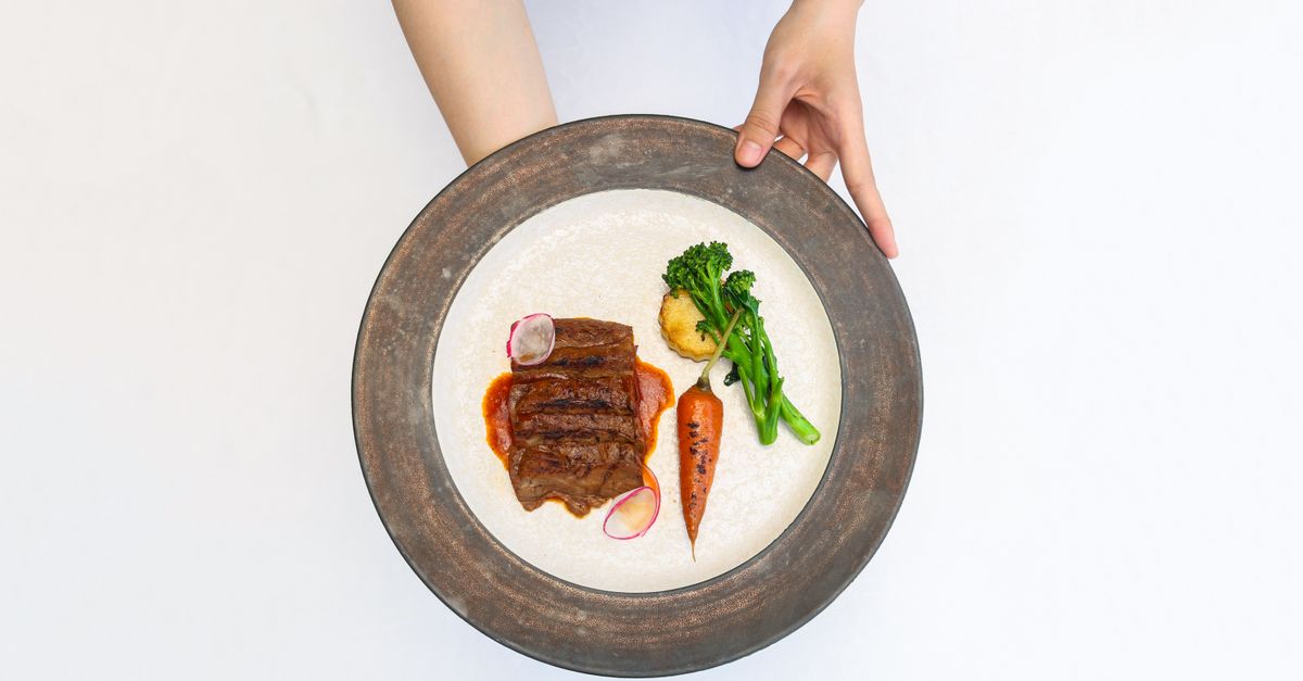 Drizzling miso dressing over roasted broccoli in a white bowl