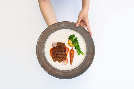 Overhead shot of elegant steak dish with vegetables on a white background. Modern cuisine concept.