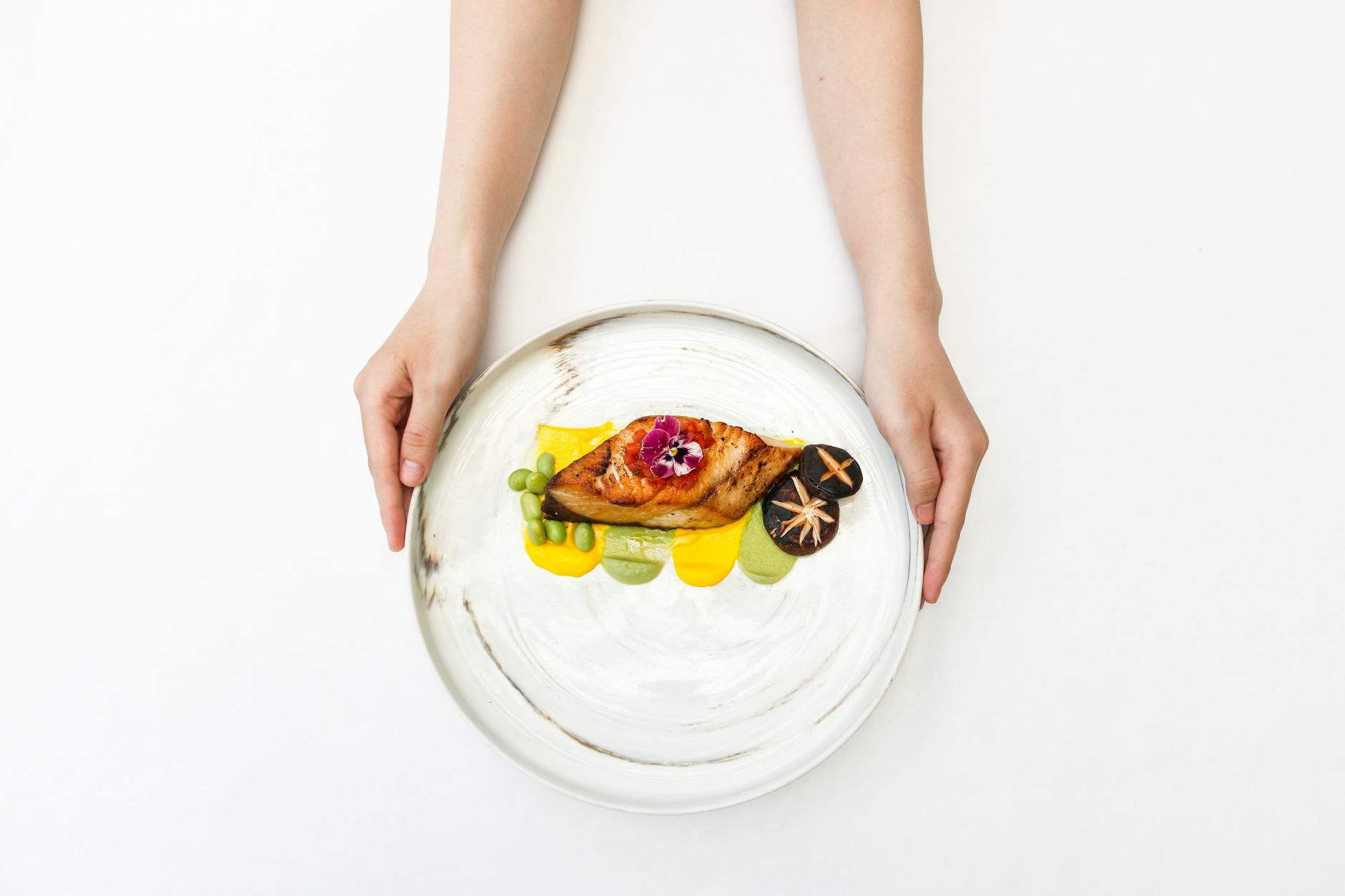 Delicious gourmet presentation with chicken, shiitake mushrooms, and edible flower on a white plate. Delicious gourmet presentation with chicken, shiitake mushrooms, and edible flower on a white plate.