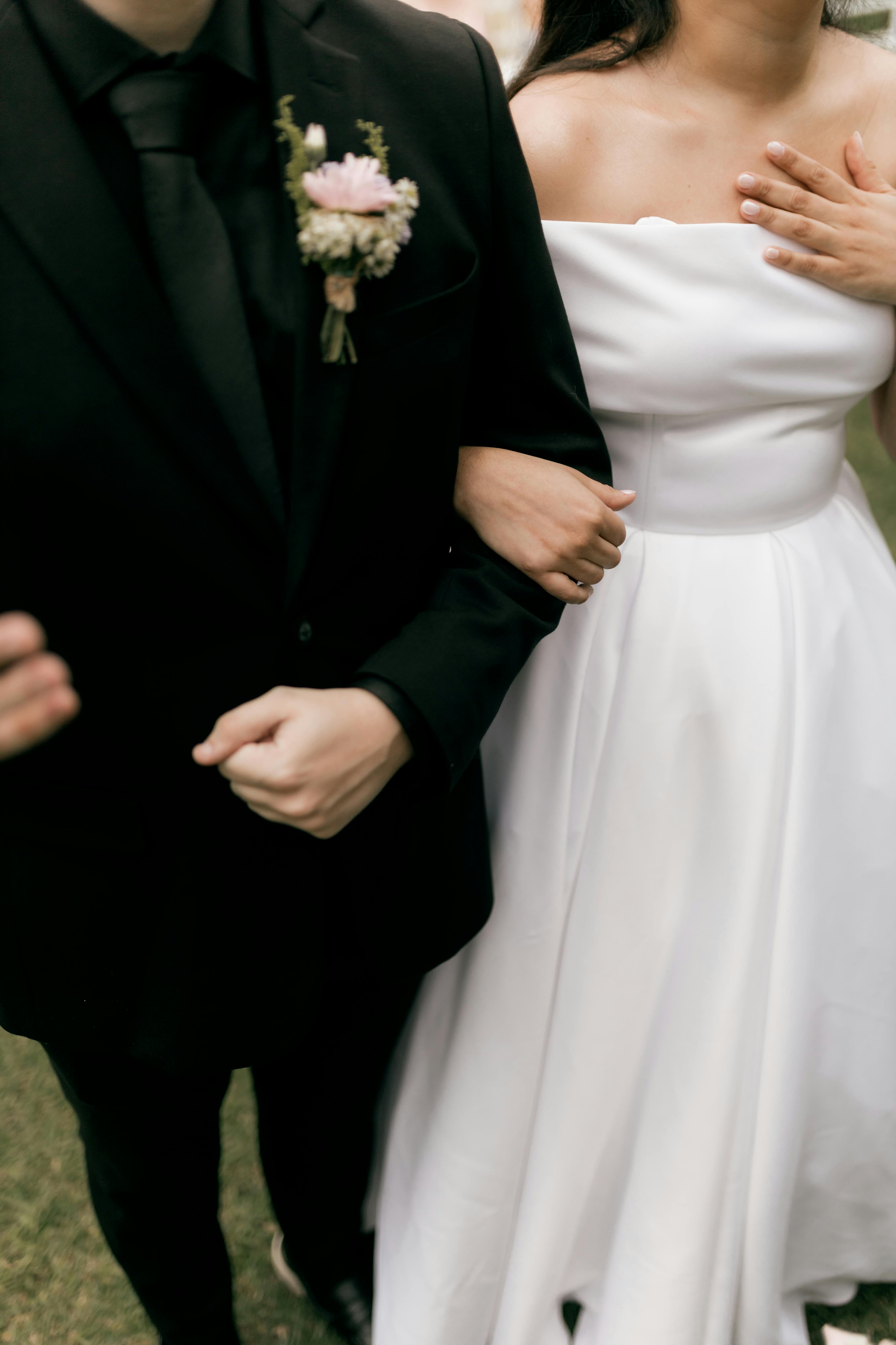 Gratuit Les mariés se tiennent la main, vêtus de tenues de mariage classiques noires et blanches. Photos