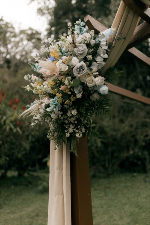 Free Beautiful floral arrangement with roses and greenery on a wooden wedding arch outdoors. Stock Photo