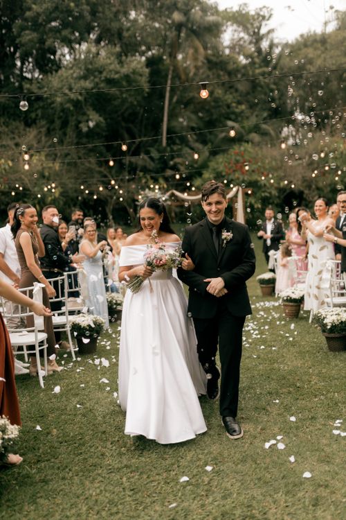 Free Happy couple walking down the aisle in an outdoor wedding ceremony. Stock Photo