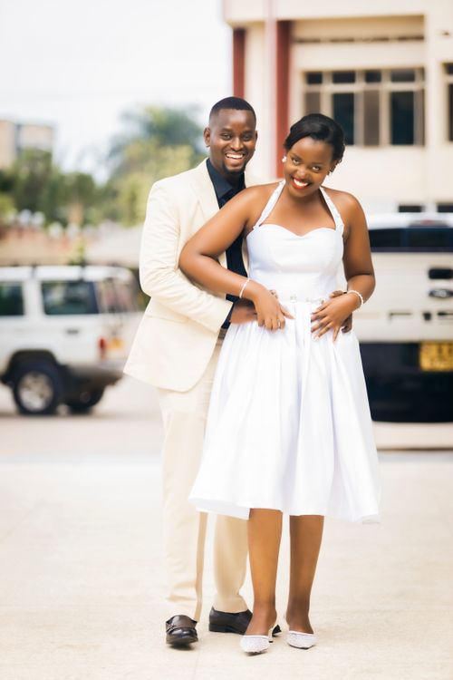 Free Smiling couple in formal attire embracing outdoors with elegant background. Stock Photo