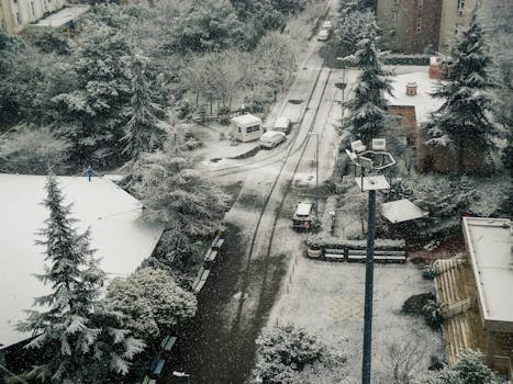 Aerial view of an urban street blanketed by snow during winter, creating a serene landscape.