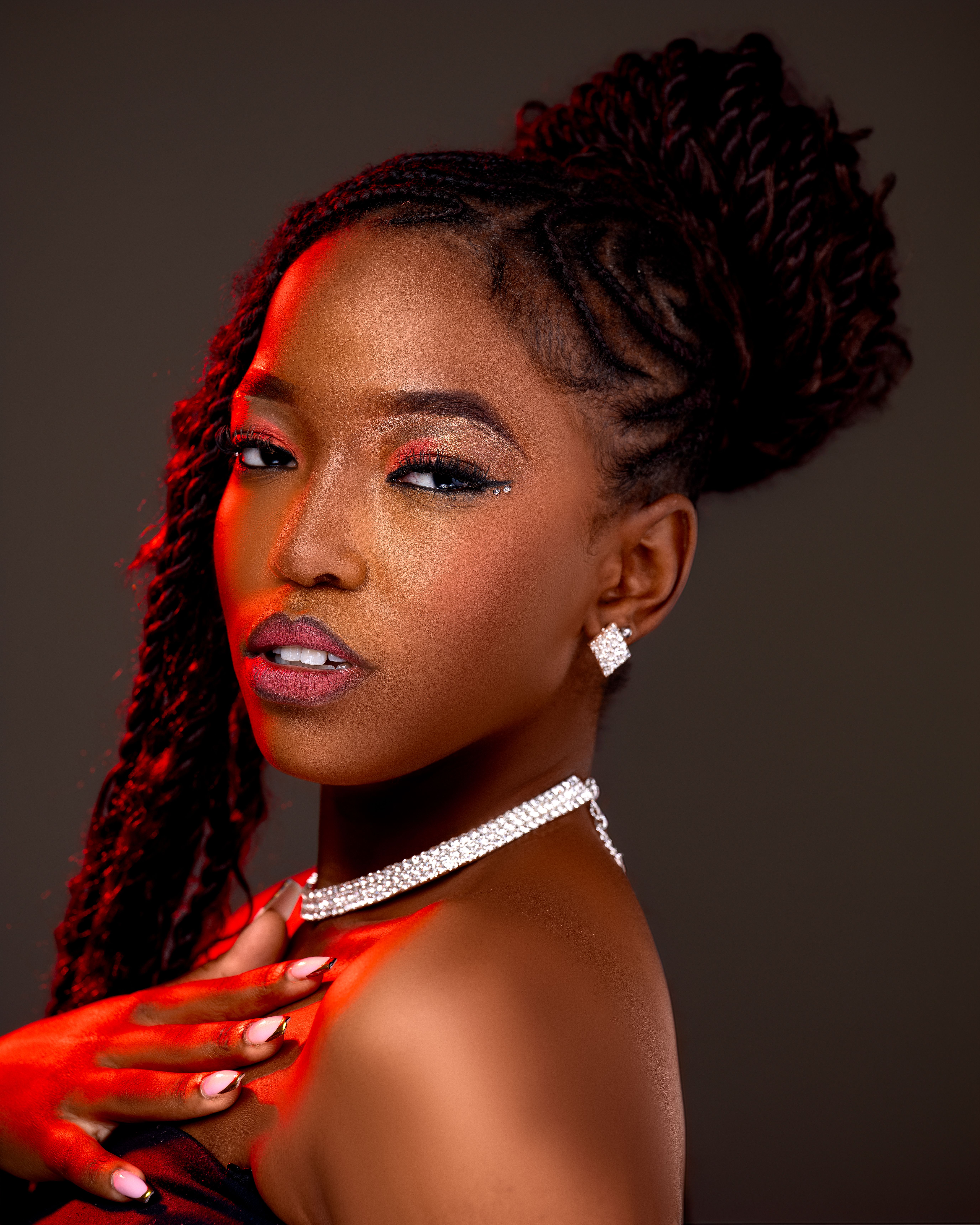 Elegant portrait of a woman with braided hair, wearing pearl jewelry and glamorous makeup.