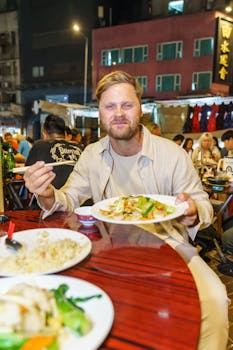 Man savoring street food at bustling night market, lively atmosphere.
