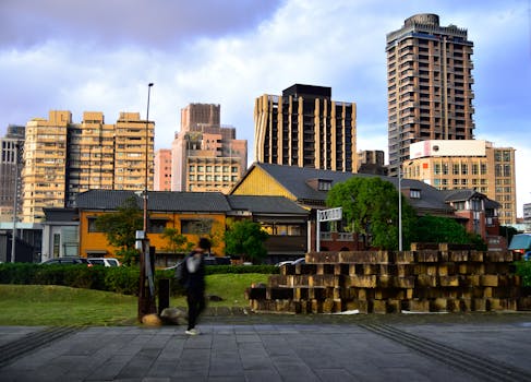 Modern and traditional architecture in Taipei City, Taiwan, captured at dusk with a blurred pedestrian.