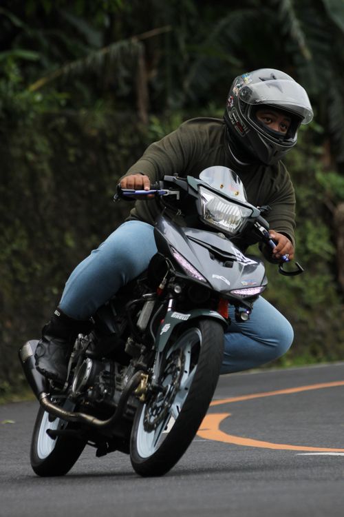 Free Motorcyclist skillfully navigating a sharp turn on a winding road. Stock Photo