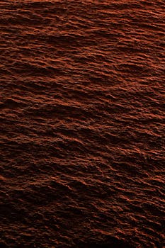 A captivating view of ocean waves tinted red by the setting sun, creating a mesmerizing pattern.