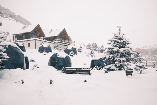 Scenic snowy landscape with geodesic domes and pine trees, perfect for winter glamping.