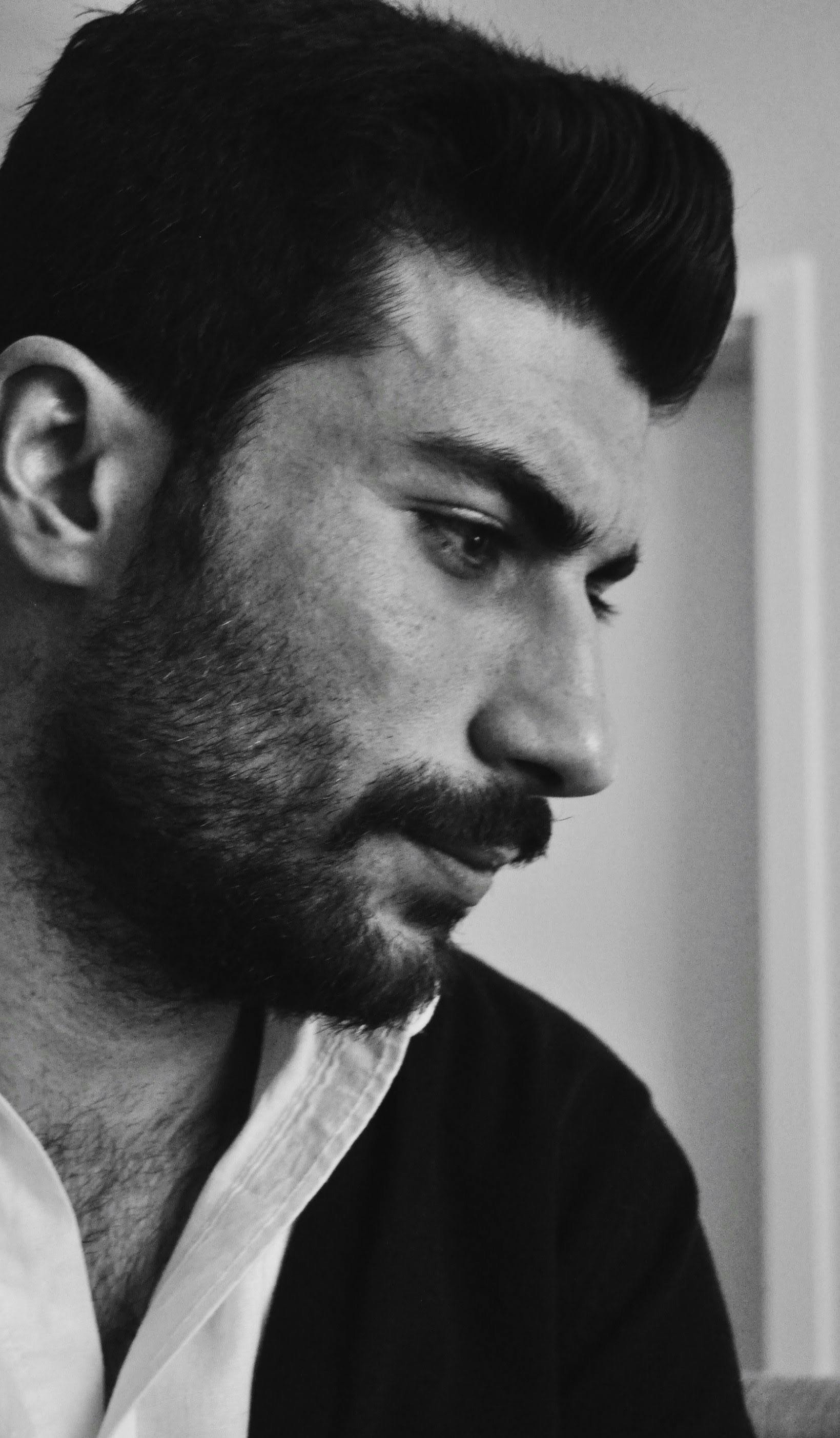 Introspective black and white portrait of a thoughtful man indoors.