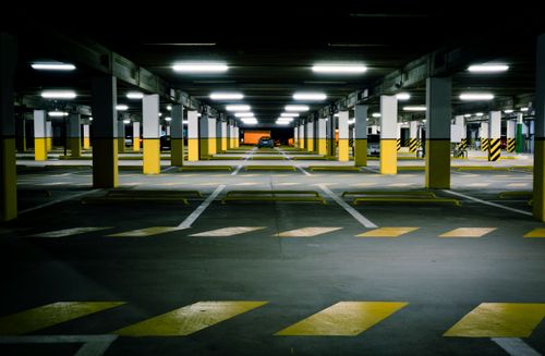 Free View of a modern underground parking garage with bright lighting and empty parking spaces. Stock Photo