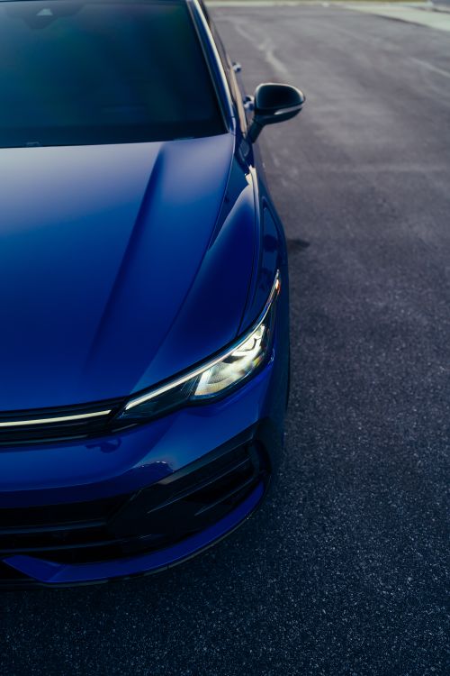 Free Close-up of a sleek blue car parked on an empty road, showcasing its modern design. Stock Photo
