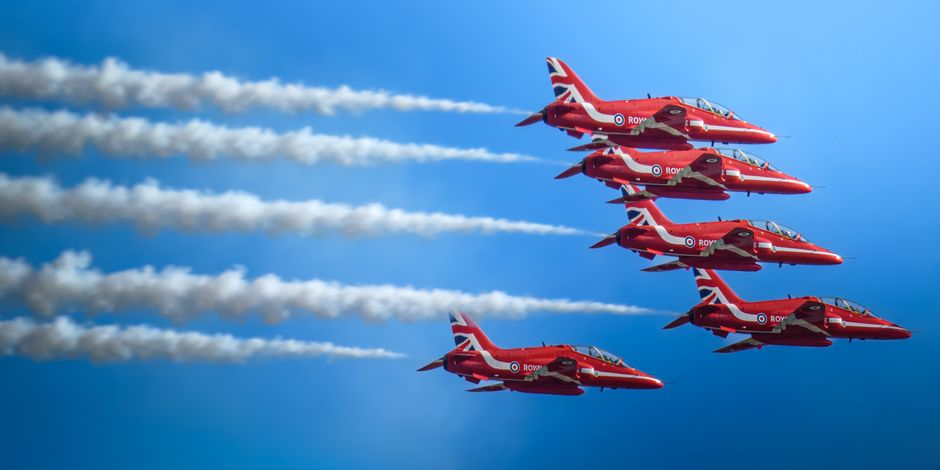 Dynamic aerial display by the Red Arrows showcasing precision flying in a clear blue sky.