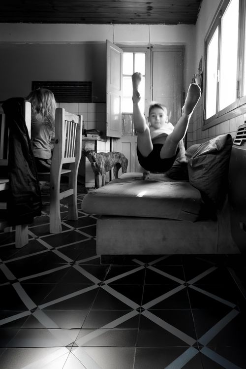 Free Monochrome indoor scene of a child playing on a couch, capturing movement and stillness. Stock Photo