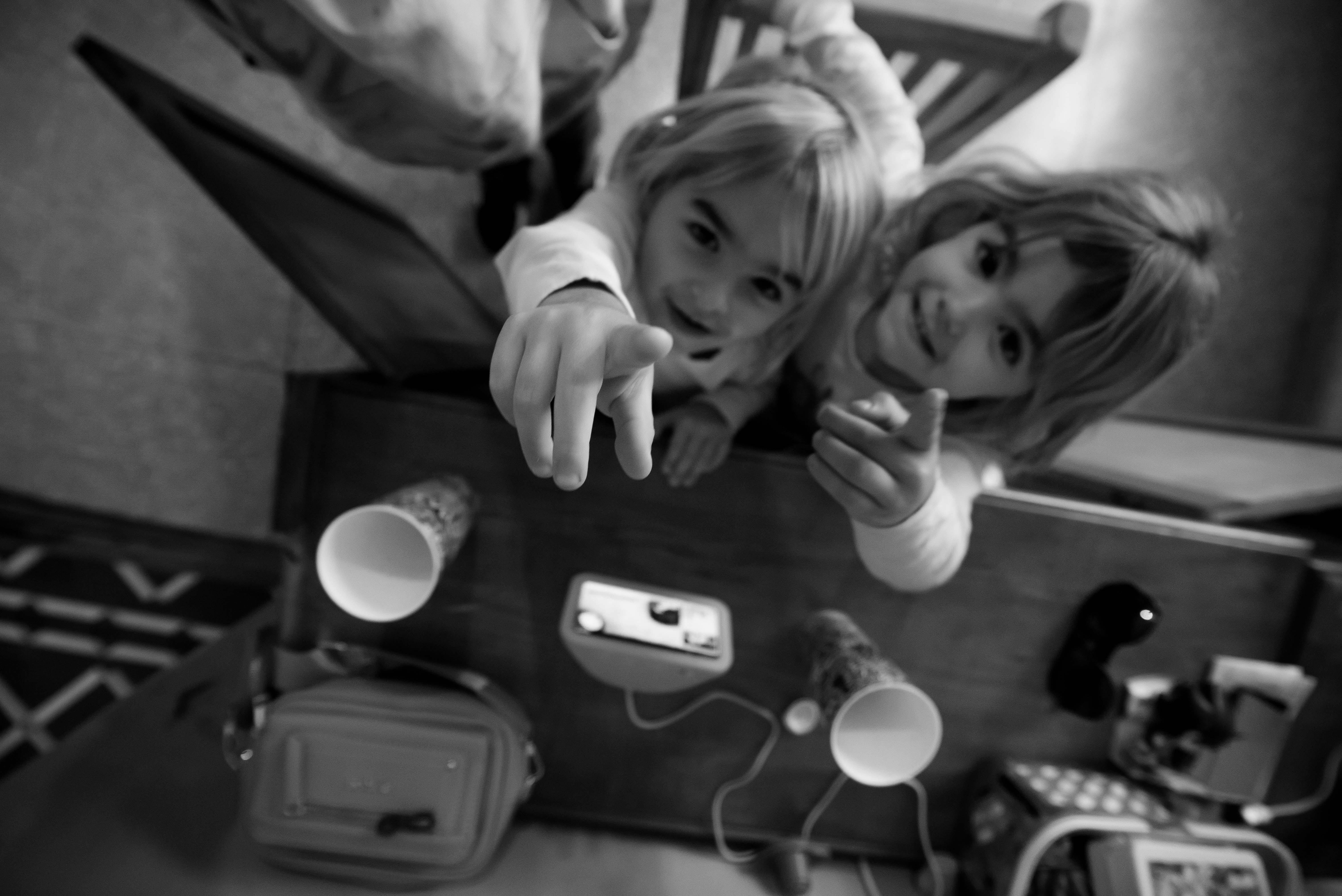 Gratis Immagine in bianco e nero di due bambini giocosi che si avvicinano alla telecamera in un interno. Foto a disposizione