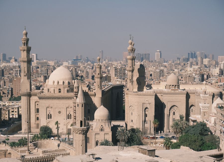 Scenic aerial view of Cairo with the iconic Mosque-Madrassa of Sultan Hassan and city skyline.