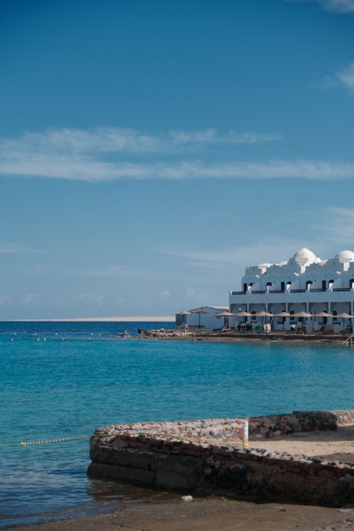 Free Beautiful mediterranean seaside resort with clear blue waters and white buildings under a sunny sky. Stock Photo