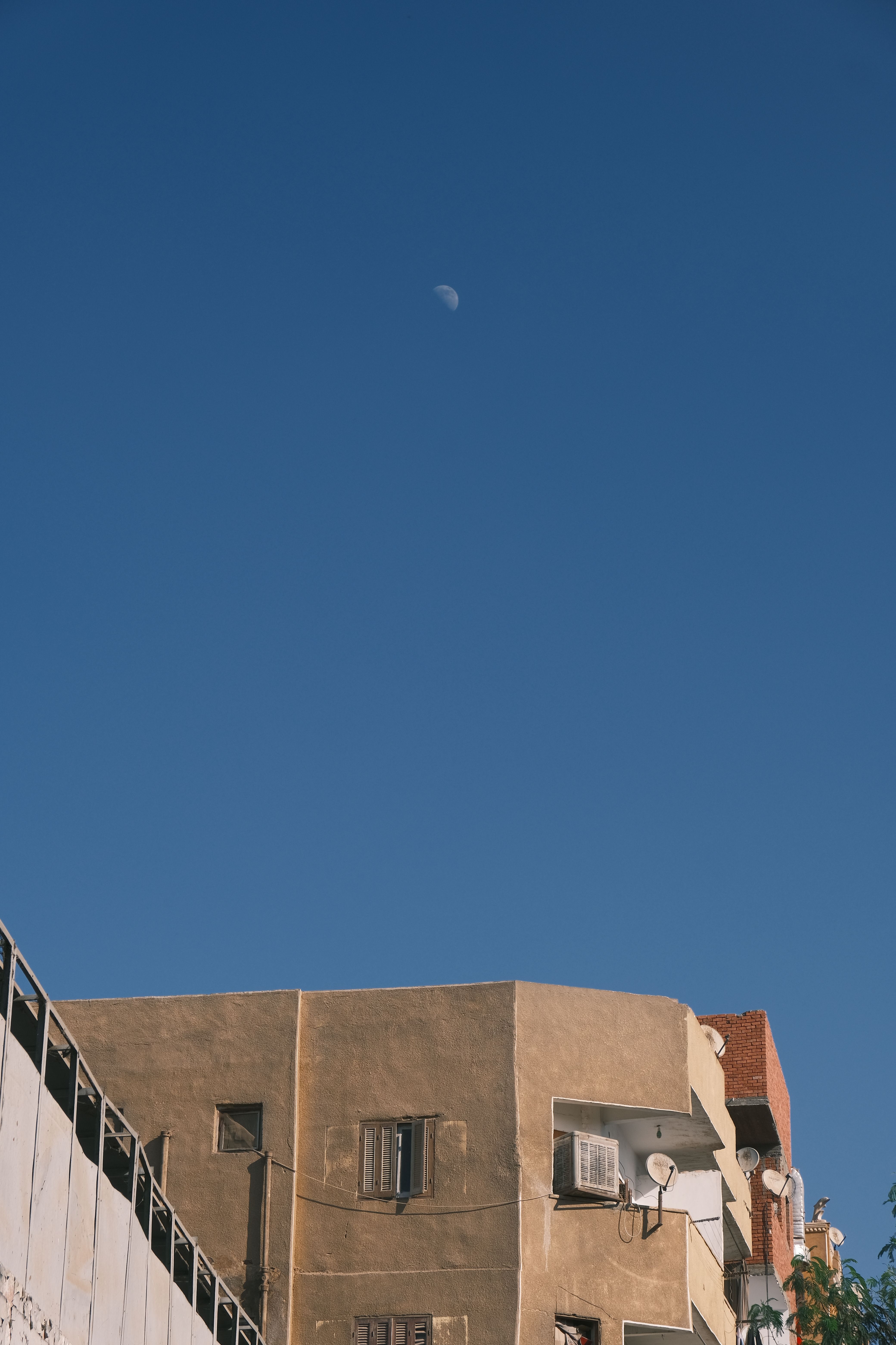 Urban Building Under Clear Blue Sky with Moon · Free Stock Photo
