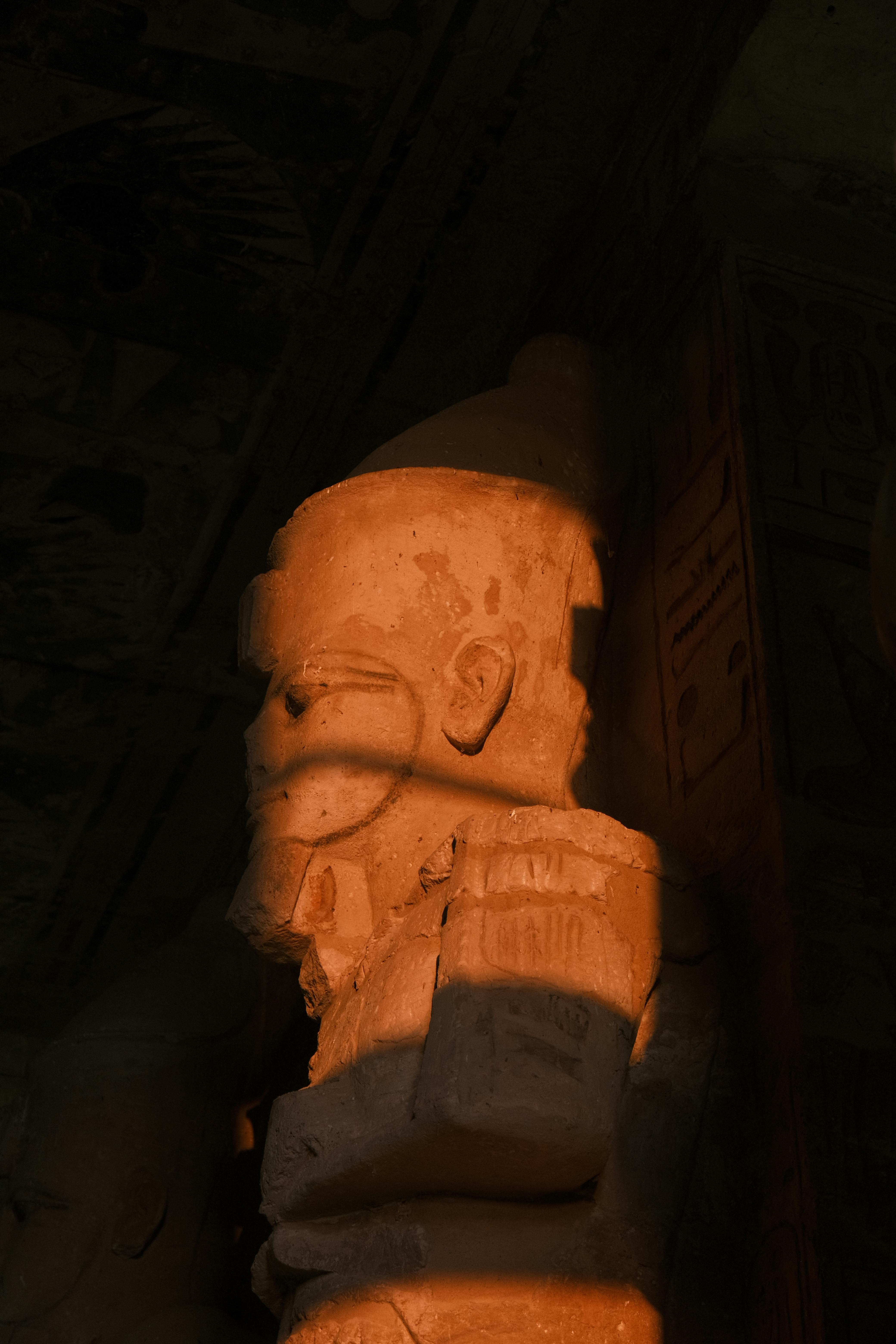 gratis Zijaanzicht van een oud-Egyptisch standbeeld, verlicht door warm, dramatisch licht. Stockfoto